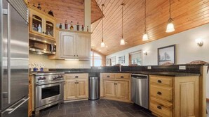 A modern kitchen with wooden cabinets, stainless steel appliances, and pendant lighting.