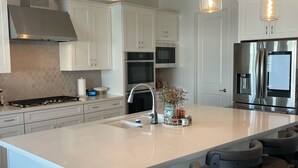 A modern kitchen with white cabinets, stainless steel appliances, and pendant lighting. - Arizona retreat! Hiking trails, 15 mins. to Downtown. Heated community pool. (Phoenix)