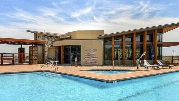 A modern pool area with a clear blue pool, lounge chairs, and a building with large windows and a stone facade. - Arizona retreat! Hiking trails, 15 mins. to Downtown. Heated community pool. (Phoenix)