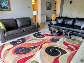 Ein Wohnzimmer mit zwei schwarzen Ledersofas, einem Couchtisch und einem bunten Teppich.