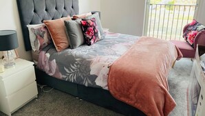 Ein Schlafzimmer mit Bett, Nachttisch und Blick ins Freie.