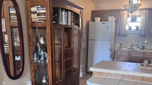 Cozinha com armário de madeira, geladeira e área de bar com banquetas.