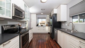 A modern kitchen with white cabinetry, stainless steel appliances, and a wooden floor.