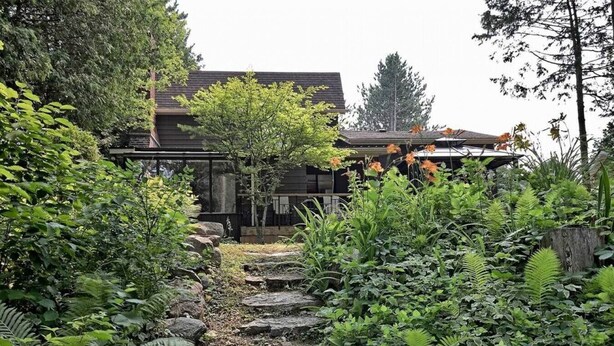A garden pathway leading to a house with a dark roof and a wooden fence. - Whispering Pines Riverside Getaway (Kawartha)