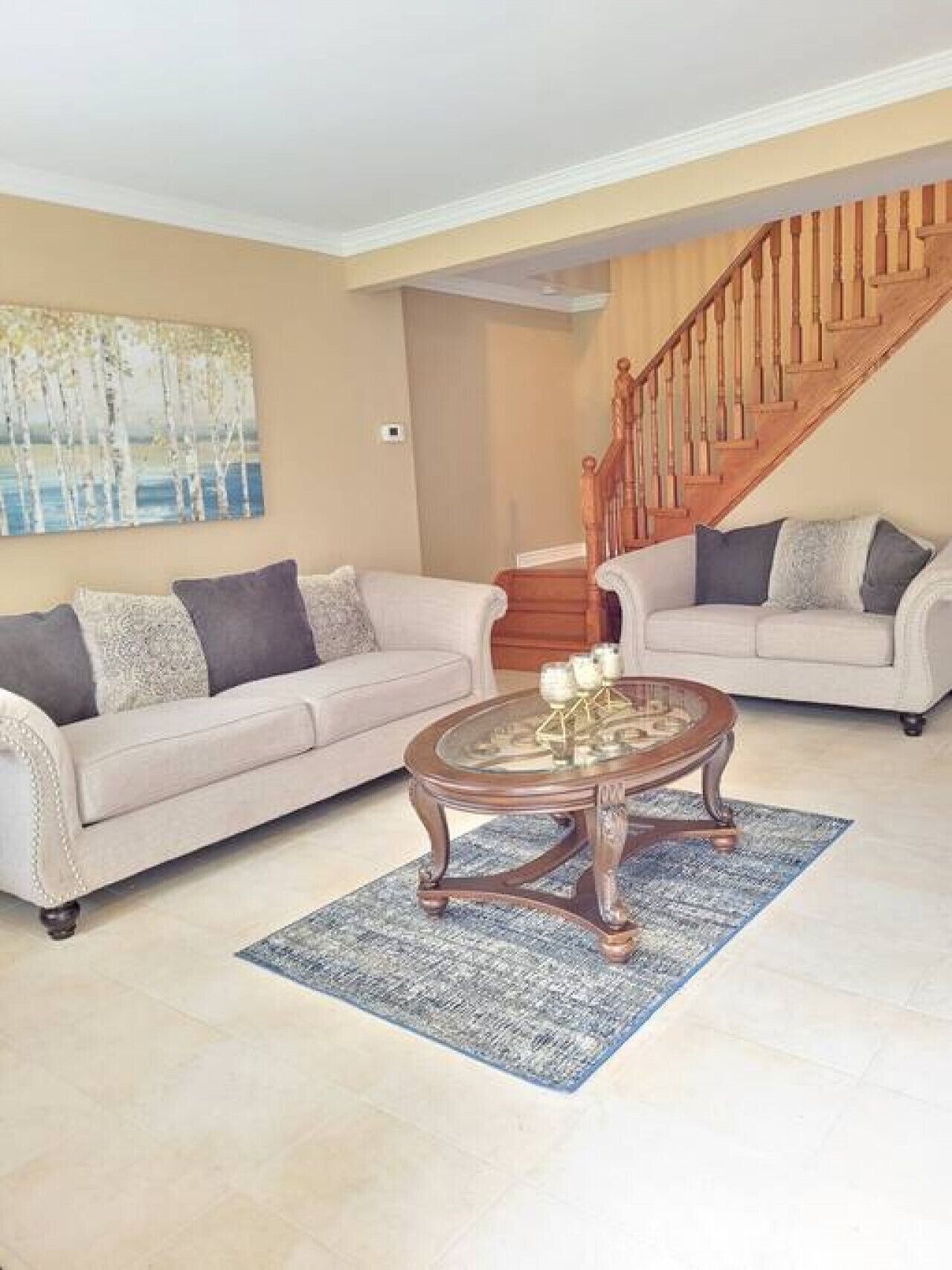 Ein Wohnzimmer mit zwei Sofas, einem Couchtisch und einer Treppe.