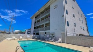Un hôtel à plusieurs étages doté d’une piscine, de balcons et d’un panneau indiquant une zone où la baignade est interdite.
