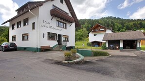 A two-story building with a balcony, a bench outside, and a car parked in front. - Cozy vacation apartment in spa town in the southern Black Forest with mountain view, garden & Wi-Fi (Todtmoos)