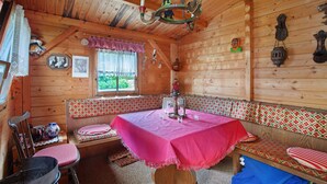 A wooden cabin with a dining table, bench seating, and a chandelier. - Cozy vacation apartment in spa town in the southern Black Forest with mountain view, garden & Wi-Fi (Todtmoos)