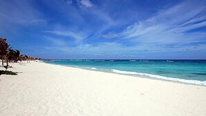 En strand med hvidt sand og krystalklart, blåt vand.