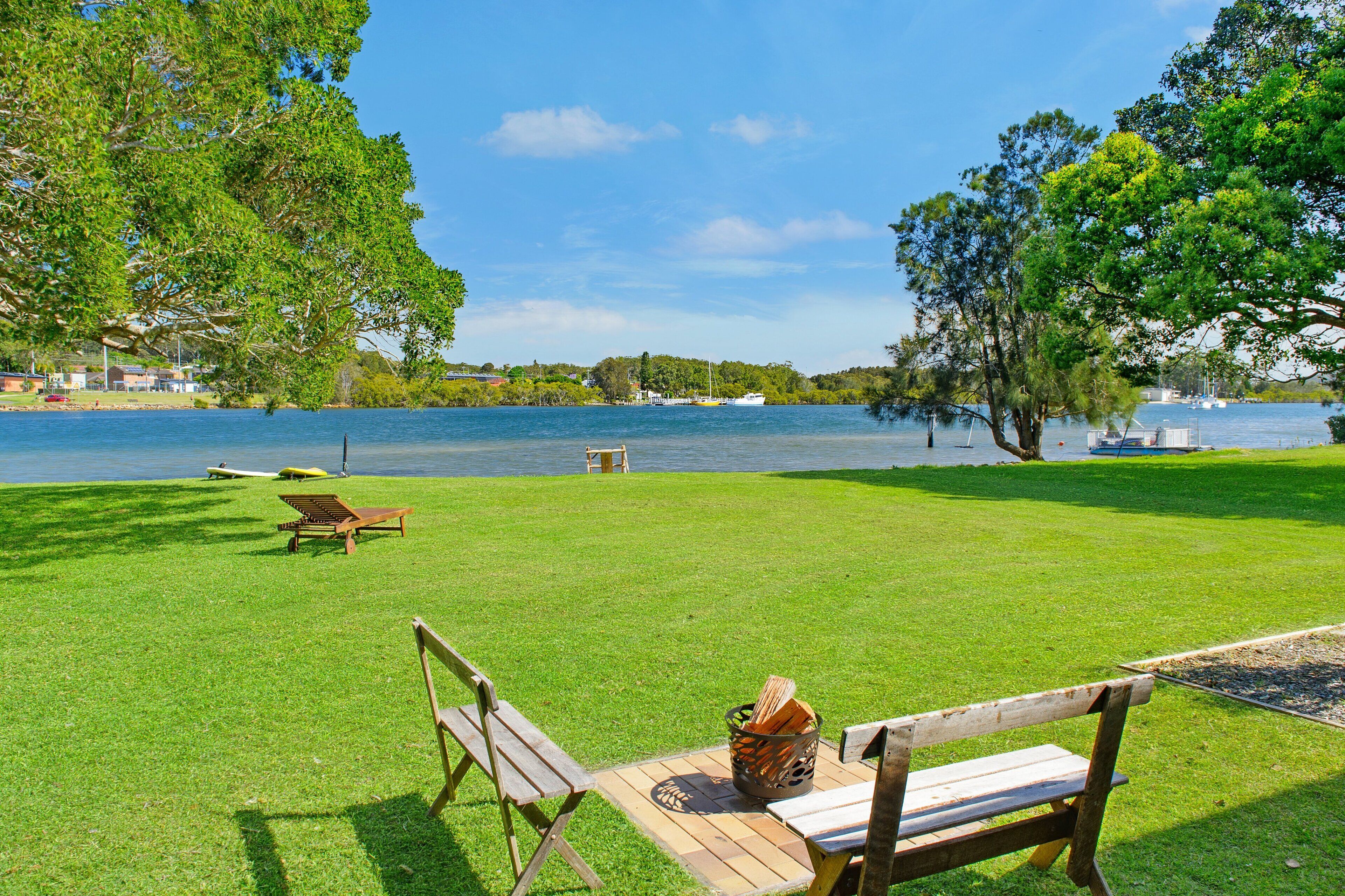 A grassy area with wooden benches and a picnic table by a lake.