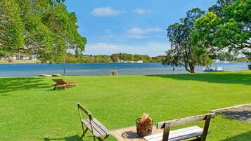 A grassy area with wooden benches and a picnic table by a lake.
