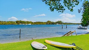 Zona verde a orillas del lago con tablas de remo y un bote.