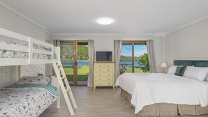 Un dormitorio con literas, un escritorio y un televisor, y vistas a un lago.