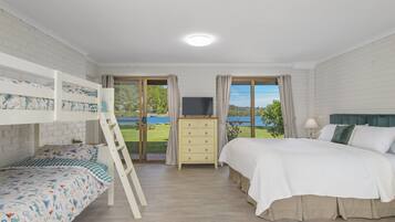 A bedroom with a bunk bed, a desk with a TV, and a view of a lake.