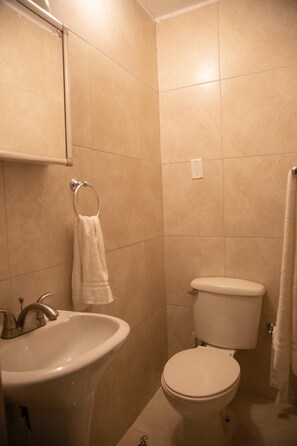 A bathroom with beige tiles, a sink, a toilet, and a towel rack. - Cozy Santurce Apt - Near Condado, Old San Juan & Beach (San Juan)