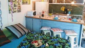 A compact kitchen with a microwave, stools, and a small dining area. - Ninamu Studio (Papeete)