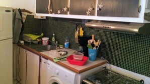 A compact kitchen with a washing machine, a sink, and a stove. - Ninamu Studio (Papeete)