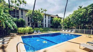 A swimming pool with lounge chairs and a building in the background. - Surf Cove - Ocean - Jeep  (Kihei)