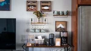 A kitchen with a TV, coffee maker, mugs, and decorative items on the counter. - South Main Chalet- Luxury living in BV- STR-120 (Buena Vista)