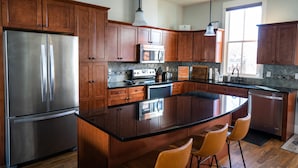 A modern kitchen with wooden cabinets, stainless steel appliances, and a central island with bar stools. - South Main Chalet- Luxury living in BV- STR-120 (Buena Vista)