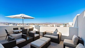 A rooftop patio with outdoor furniture, a table, and an umbrella. - Serenity Shores #80 (St. George)