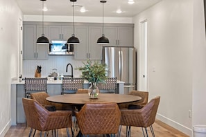 A modern kitchen with grey cabinets, stainless steel appliances, and a central island with seating.