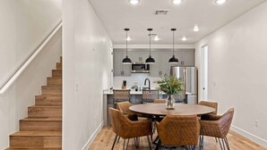 A modern kitchen with a central island, pendant lighting, and a dining area with a round table and chairs. - Serenity Shores #80 (St. George)