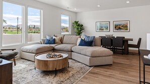 A modern living room with a sectional sofa, a round coffee table, and a dining area with chairs and a table. - The Berber at Desert Color by RedAwning (St. George)