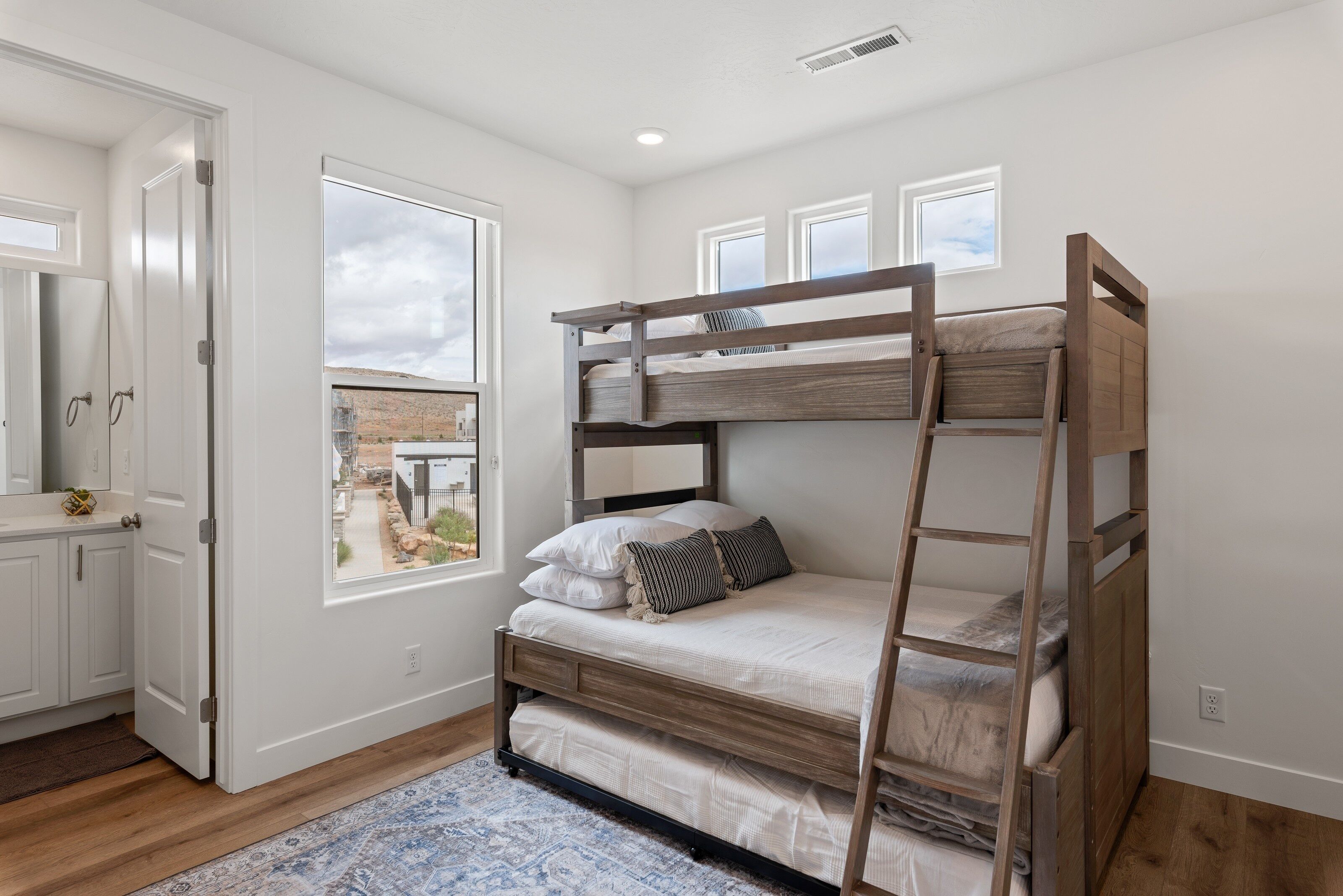 A bunk bed room with a view of a desert landscape through a large window.