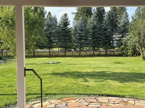 A well-maintained lawn with a stone patio and a wooden fence in the background. - Charming Dover Home, with Large Fenced Yard and Garden View (Dover)