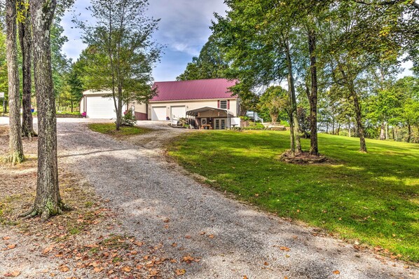 A rural property with a gravel driveway leading to a large garage and a covered outdoor area. - Mammoth Cave Rental on 50 Acres: Shared Amenities (Mammoth Cave)