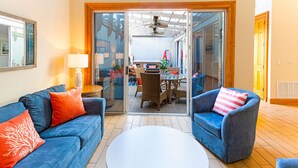 Una sala de estar moderna con un sofá azul, una mesa de centro redonda y un sillón azul con un cojín a rayas.
