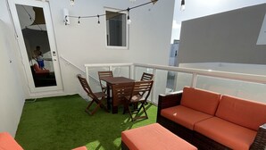 A balcony with artificial grass, wicker furniture, and string lights. - Modern studio fully equipped (Doral)