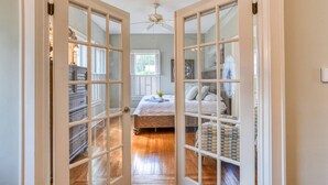 A hallway leading to a bedroom with a bed, a dresser, and a ceiling fan. - Close to Historic Downtown, River, Kayaks Included with Short Walk to Launch, $300 in Free Tickets! (St. Augustine)