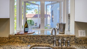 A kitchen with a granite countertop, a stainless steel sink, a wine bottle, and a pitcher. - Close to Historic Downtown, River, Kayaks Included with Short Walk to Launch, $300 in Free Tickets! (St. Augustine)