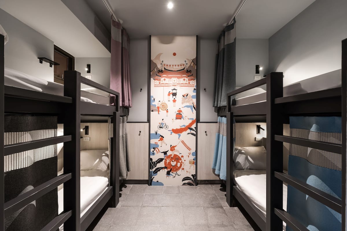 A room with bunk beds, a decorative wall, and a small table.