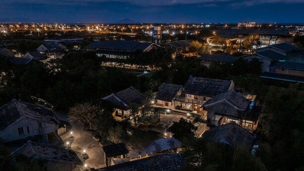 Een traditionele Japanse stad 's nachts, met verlichte gebouwen en een rivier.