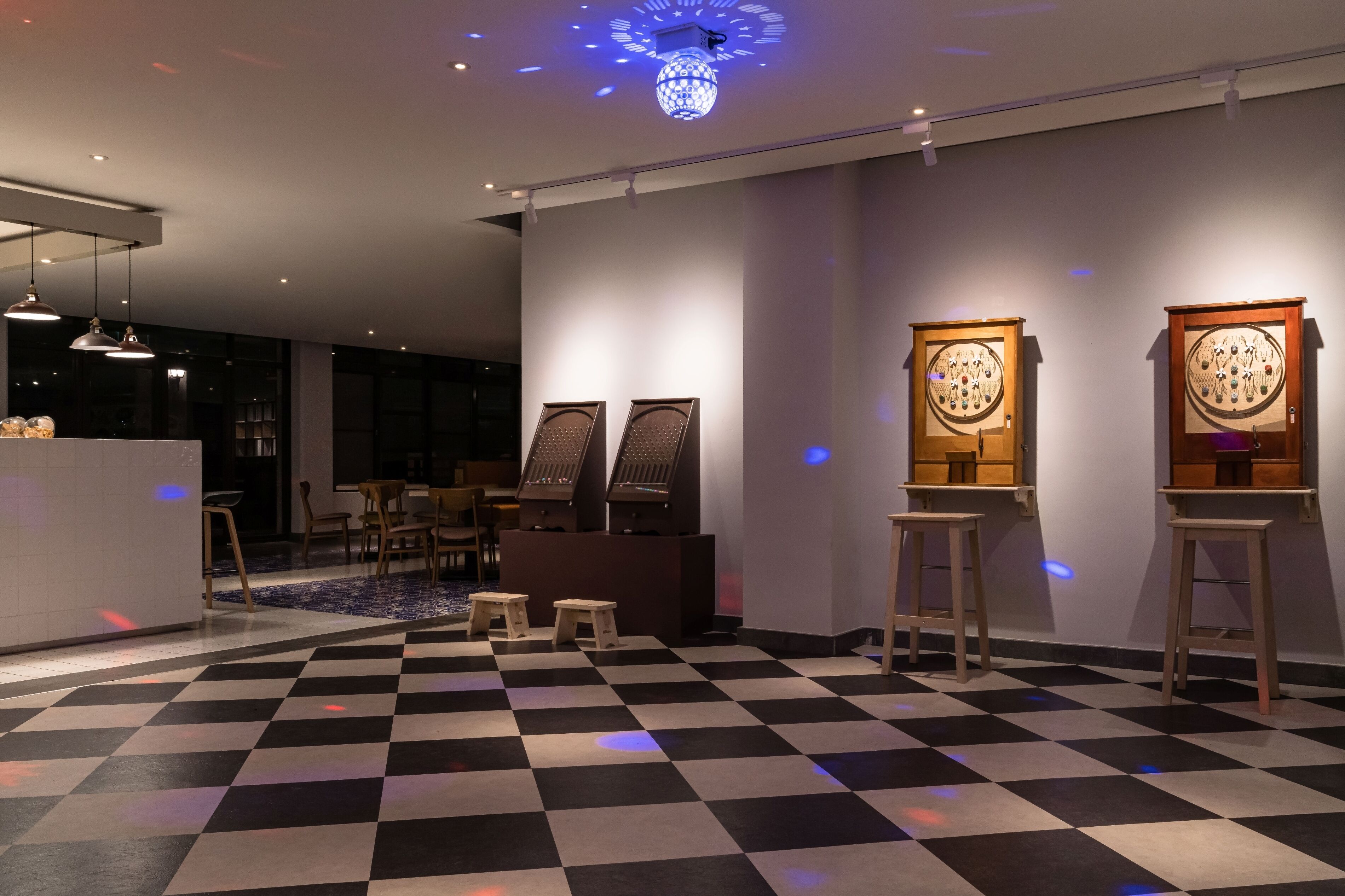 A modern hotel lobby with a checkered floor, a reception desk, and two wall-mounted display cases.
