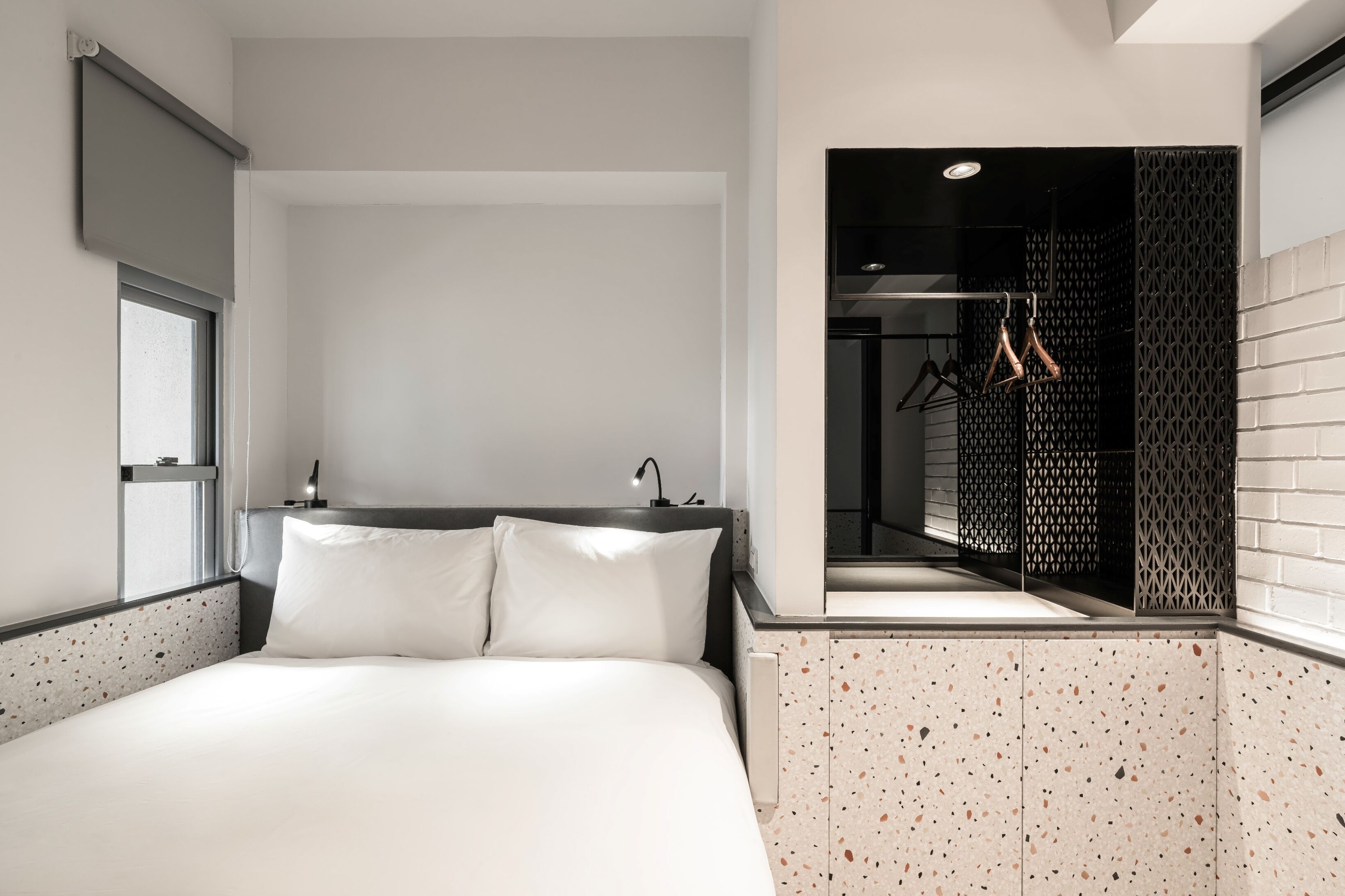 Una habitación de hotel moderna con una cama grande, un vestidor y vistas de la ciudad a través de una ventana.
