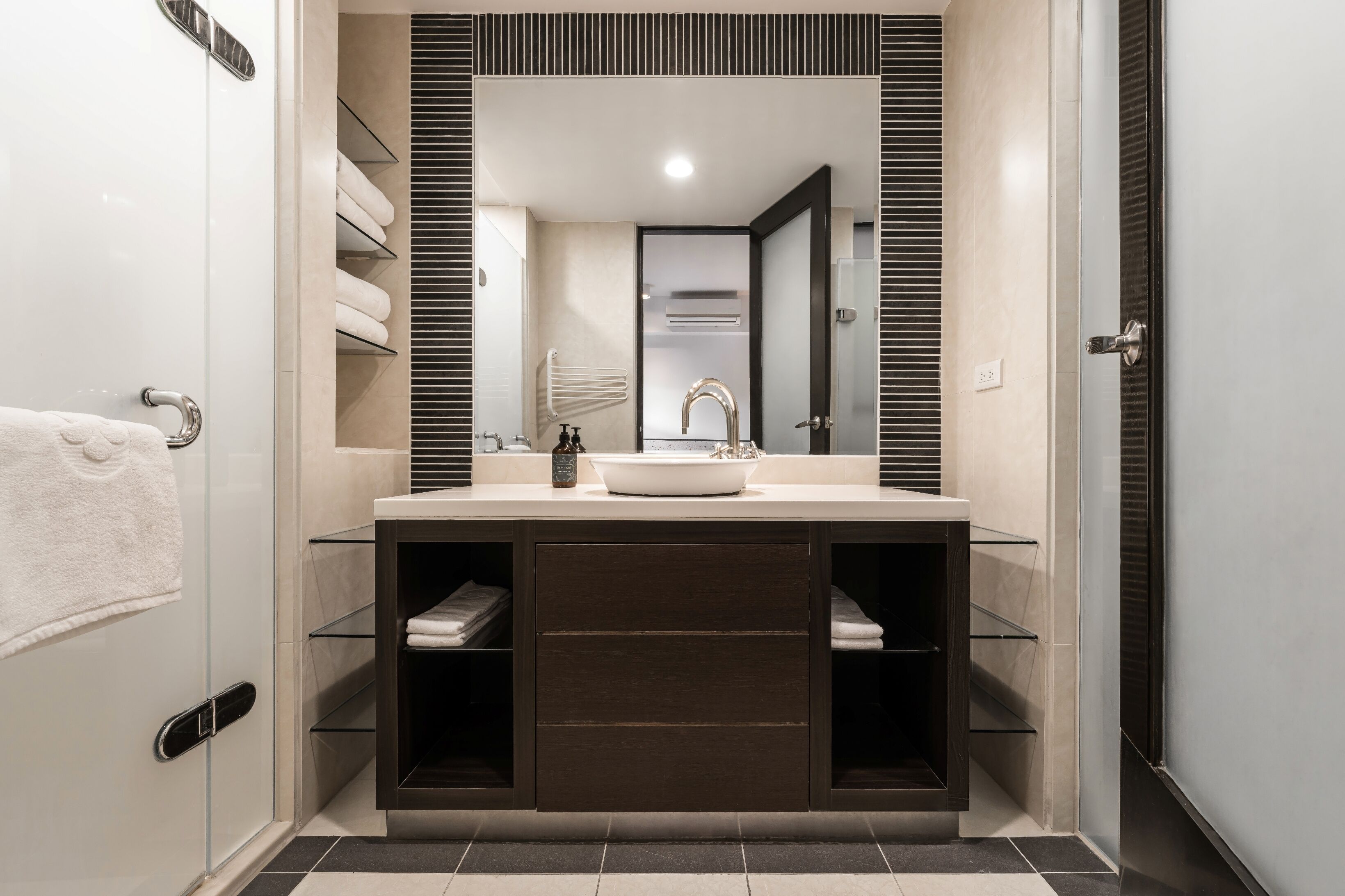 Un baño moderno con un espejo grande, un lavamanos y un perchero para toallas.