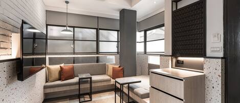 Una cocina moderna con estufa integrada, un comedor con mesa y sillas, y una zona de estar con sofá y cojines.