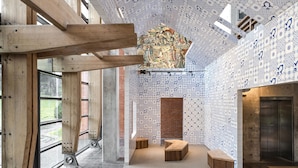 Een modern interieur met zichtbare houten balken, behang met patroon en een centraal decoratief element.