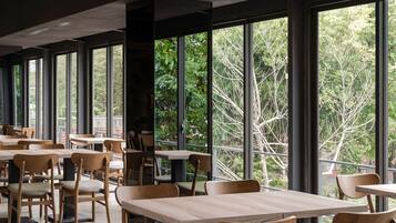 A spacious dining area with large windows, wooden tables, and chairs.