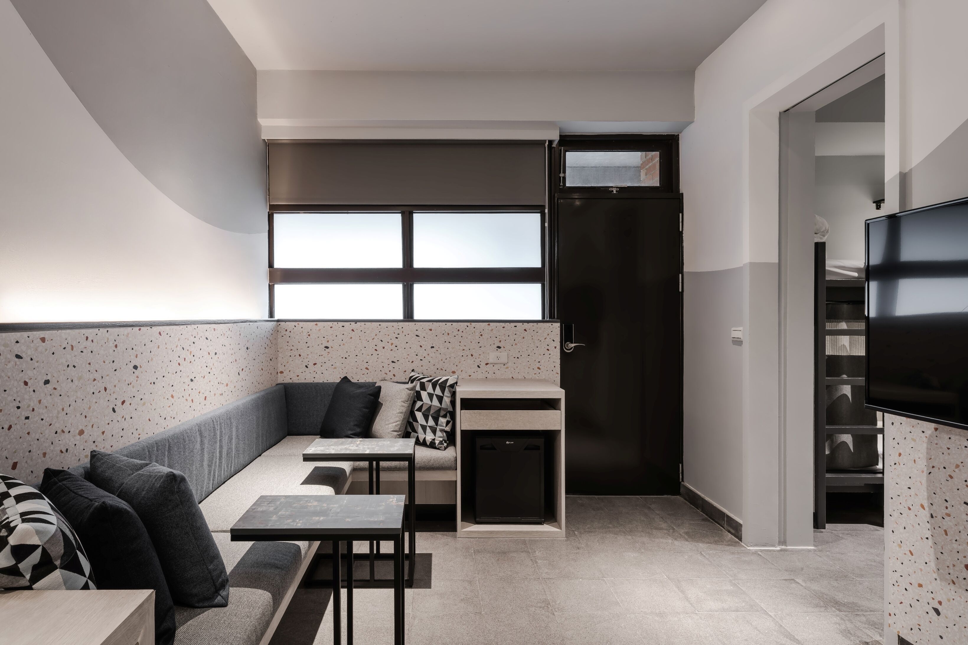 Un espacio habitable moderno y funcional, con kitchenette, zona de estar y televisor.