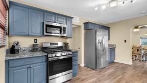 A modern kitchen with blue cabinets, stainless steel appliances, and a wooden floor. - Midtown Territorial Home Beautifully Updated + Convenient  2 miles U of A (Tucson)