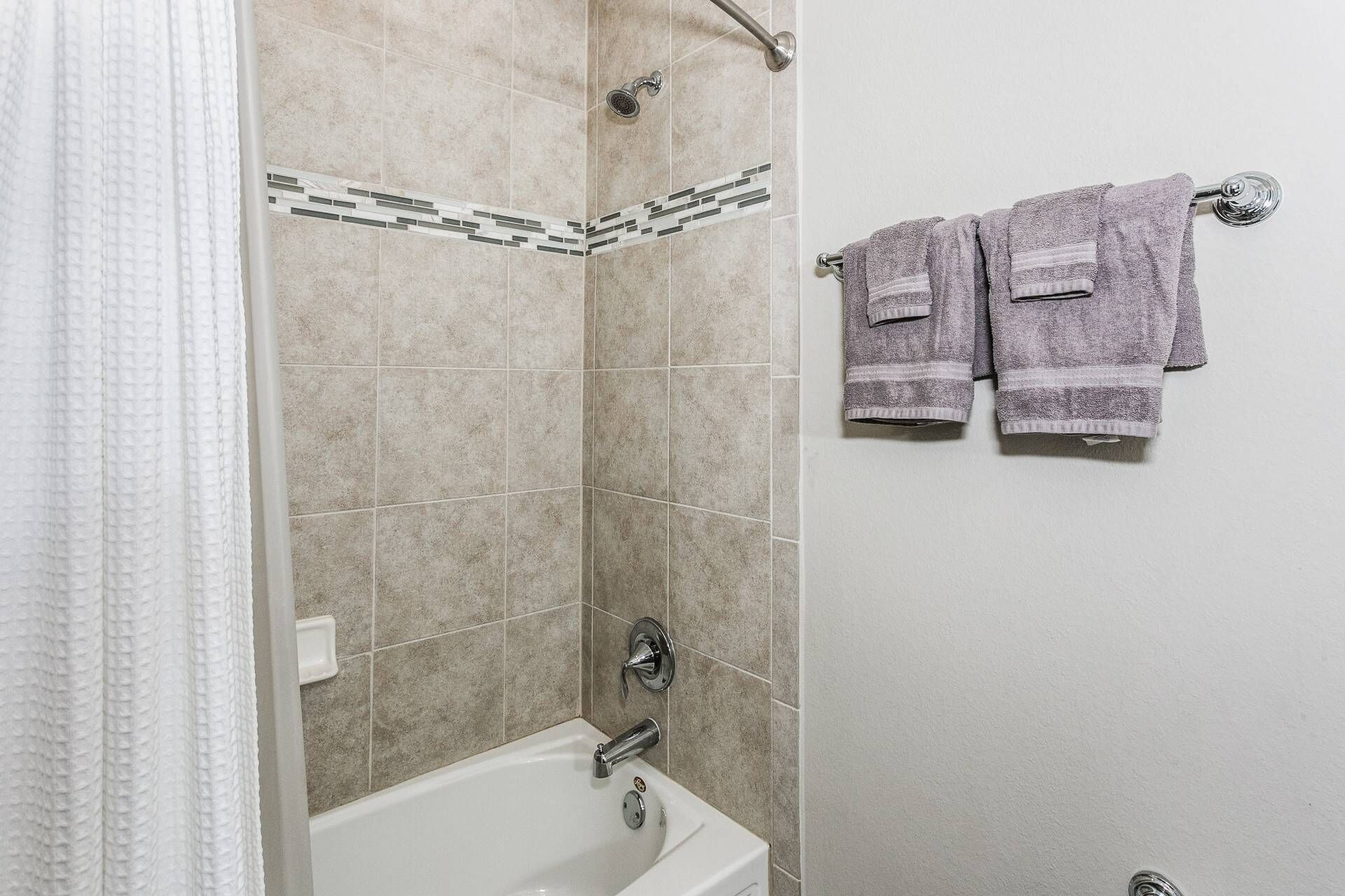 Ein Badezimmer mit einer Badewanne, einer Dusche und zwei Handtüchern, die an einem Wäscheständer hängen.