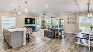 A spacious kitchen with a large island, bar seating, and a dining area with a wooden table.
