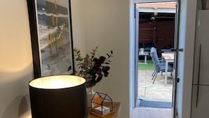 Une table en bois avec une lampe, un tableau encadré et un vase avec des plantes, le tout placé dans un couloir.