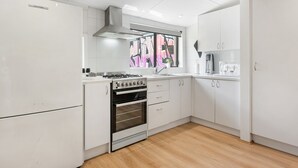 Une cuisine moderne avec des meubles blancs, une cuisinière à gaz, un four et une fenêtre donnant sur l’extérieur.