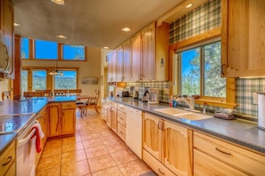 A spacious kitchen with wooden cabinets, a large island, and a view of the outdoors through the windows.
